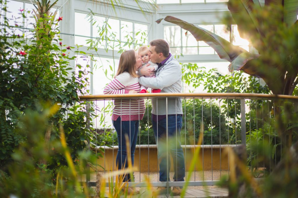 Parents kissing toddler.